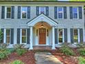 Inviting front entrance with brick walk, wood door, classic pillars, and lovely landscaping at 4830 Broad Hollow Dr, Charlotte, NC 28226