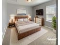 Comfortable staged main bedroom with a king bed, soft carpet, and a mounted TV for relaxation at 4906 Lynn Lee Cir, Charlotte, NC 28269