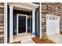 Inviting entryway with a black door, white trim, and stone accents, enhanced by a security system and manicured landscaping at 522 Trading Post Ln, York, SC 29745