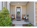 Charming front door with wreath, flanked by chairs, welcomes guests to the inviting home at 6450 Keeton Ln, Harrisburg, NC 28075