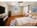 Stylish bedroom with hardwood floors, a ceiling fan, and a barn door leading to the ensuite bathroom, offering privacy at 867 Meadow Hill Ct, Lincolnton, NC 28092