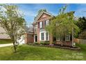 Inviting brick home featuring black shutters, flowering trees, and well-maintained landscaping at 12729 Mcginnis Ln, Huntersville, NC 28078