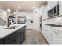 Spacious kitchen with white cabinets, a large island, stainless steel appliances, and hardwood floors at 141 Rhuidean Ct, Troutman, NC 28166