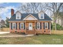 Charming brick home featuring a welcoming front porch, dormer windows, a well-manicured lawn, and mature trees at 1815 Townes Ct, Rock Hill, SC 29730