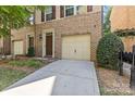 Brick townhouse featuring a one-car garage, driveway, front door, and some landscaping in front at 225 Lincoln St, Charlotte, NC 28203
