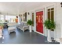 Cozy porch with wicker furniture, plants and a red front door leading into the home at 322 4Th Sw St, Hickory, NC 28602