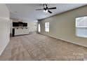 Open-concept living area with carpet flooring, a ceiling fan, and access to the kitchen at 620 Weyburn Nw Dr, Concord, NC 28027