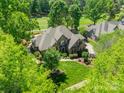 Stunning aerial view of a brick home, surrounded by lush greenery and a golf course at 13358 Bally Bunnion Way, Davidson, NC 28036