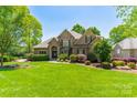 Charming brick home boasts manicured landscaping, a lush lawn, and mature trees at 13358 Bally Bunnion Way, Davidson, NC 28036