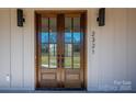 Close-up of the front door with wood frame, glass panels, and modern lighting at 2321 Ivey Church Rd, Maiden, NC 28650