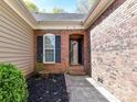 Close-up of brick entryway with black door, trim, and manicured shrubbery at 7507 Reedy Creek Rd, Charlotte, NC 28215