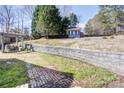 Backyard features a shed with shutters, a stone wall, grass and patio area with grill at 105 Partridge Bluff Ne Dr, Concord, NC 28025