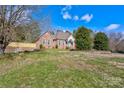 Charming brick home with a well-manicured lawn, mature trees, and blue front door at 105 Partridge Bluff Ne Dr, Concord, NC 28025