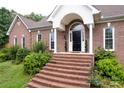 Close up of brick staircase leading up to the front door with white pillars and lush landscaping at 105 Partridge Bluff Ne Dr, Concord, NC 28025