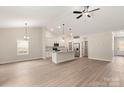 Open-concept living space with wood floors, white kitchen with island, stainless appliances, and vaulted ceilings at 3512 Narrow Ln, Charlotte, NC 28215