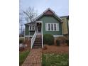 Charming green house boasts a welcoming front porch with white railings and brick pathway at 446 Windsor Ln, Statesville, NC 28677