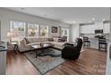 Open-concept living room featuring hardwood floors, a large sofa, and abundant natural light at 2116 Belterra Dr, Charlotte, NC 28216