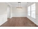 Dining room features hardwood floors, wainscoting, modern light fixture, and natural light at 3017 Woodlands Creek Dr, Monroe, NC 28110
