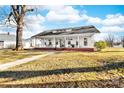Inviting white home showcasing a sprawling porch with classic columns and shaded seating areas at 308 W First St, Lowell, NC 28098