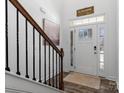 Welcoming entryway with hardwood floors, a wooden staircase, and natural light streaming through the front door at 5056 Blue Serenity Ct, Denver, NC 28037