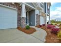 Charming townhome exterior featuring a walkway, rock facade, two garage doors, and a well-maintained landscaped yard at 1028 Grays Mill Rd, Charlotte, NC 28215