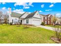 Charming white home featuring a well-manicured lawn, attached garage and lush landscaping at 13705 Queenswater Ln, Charlotte, NC 28273