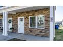 Close-up of a charming stone porch with a white door and window at 3931 Newhall Nw Dr, Hickory, NC 28601
