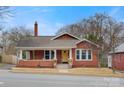Inviting red brick home with a covered front porch, yellow front door, and mature trees in a residential neighborhood at 609 2Nd Ne St, Hickory, NC 28601