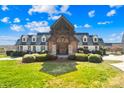 A grand exterior view of the home showcasing its brick and white siding, gabled roof, and lush landscaping at 12613 Oak Grove Rd, Stanfield, NC 28163