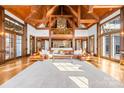 Spacious living room featuring exposed timber beams, a stone fireplace, and large windows for natural light at 12613 Oak Grove Rd, Stanfield, NC 28163