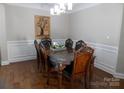 Elegant dining room with dark hardwood floors, wainscoting, chandelier, and a large wood table with seating for eight at 3500 Exbury Gardens Dr, Waxhaw, NC 28173