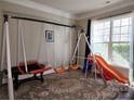 Bright playroom with a large window, carpet, and an indoor swing set with slide for hours of fun at 3500 Exbury Gardens Dr, Waxhaw, NC 28173