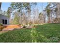Landscaped backyard featuring a wooden deck, stone fire pit, and a grassy area with tall trees at 4095 Harmattan Dr, Denver, NC 28037