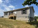 Home with gray siding, black shutters, wooden deck, and a partially finished basement at 565 Perry Rd, Troutman, NC 28166