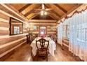 Cozy log cabin dining room featuring a wood table set for eight, enhanced by natural light and rustic charm at 1620 London Rd, Mooresville, NC 28115