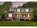 Inviting two-story home with brick facade, shutters, and landscaped front yard at sunset at 6117 Brace Rd, Charlotte, NC 28211