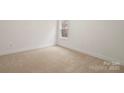 This empty bedroom features neutral carpet and a window, ready for personalization and comfortable living at 10405 Briarhurst Pl # 18, Mint Hill, NC 28227
