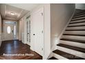 Bright foyer with hardwood floors, a decorative front door and staircase with wooden railing at 121 N Prestwick Way # 43, Mooresville, NC 28115