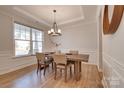 Bright dining room featuring hardwood floors, a modern chandelier, and large windows providing ample natural light at 15606 Walnut Hill Dr, Charlotte, NC 28278