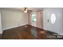 Spacious living room with hardwood floors, large window and a white front door at 4824 Harcourt Ln, Charlotte, NC 28212