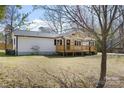 Angle view of house showing wooden front porch and new siding, with a leafless tree in foreground at 5015 Forestmont Dr, Matthews, NC 28105