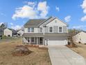 Charming two-story home with a covered porch and a two-car garage, showcasing its inviting curb appeal at 603 Smokehouse Ln, Albemarle, NC 28001