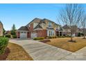 Well-maintained home with a three-car garage, long driveway, and lush landscaping on a bright, sunny day at 10415 Waxhaw Manor Dr, Waxhaw, NC 28173