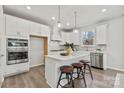 Modern kitchen featuring white cabinets, a large island, stainless steel appliances, and stylish pendant lighting at 162 Holsworthy Dr, Mooresville, NC 28115