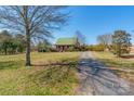 A single-Gathering home has a green metal roof and a long paved driveway, showing its serene country setting at 1847 Bertha Knight Rd, Lancaster, SC 29720