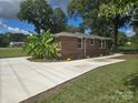 Brick home features a new concrete driveway surrounded by mature trees and flowers at 245 College E Ave, Shelby, NC 28152
