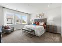 Bright bedroom featuring large windows, a plush bed, decorative art, and a cozy sitting area for relaxation at 3105 Beacon Heights Rd, Indian Land, SC 29707