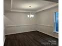 The dining room features modern dark hardwood floors, decorative trim, and an elegant chandelier at 8231 Annsborough Nw Dr, Concord, NC 28027