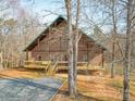 Charming brick house nestled among bare trees, featuring a spacious wooden porch at 5687 Putuptoe Pl, Norwood, NC 28128