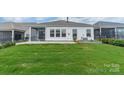 An outdoor view showing a flat, grassy backyard with patio at 1819 Lotus Ln, Denver, NC 28037